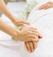 Una cuidadora sostiene la mano de su ser querido, que descansa en la cama