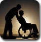 El perfil de un hombre que lleva en silla de ruedas a una mujer a la puesta del sol