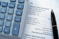 A calculator and pen on top of a cash balance sheet