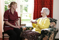 Una profesional de la salud está sentada hablando con una mujer mayor