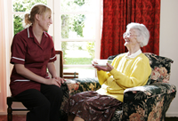 Female provider is sitting and talking to an elderly woman