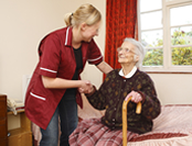 A female nurse in an assisted living facility is helping an elderly woman stand