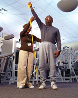 Female provider assisting elderly man exercise using tension rods