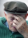 Elderly man has his eyes closed and his hand over his face