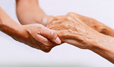 A pair of hands belonging to a younger person are helping a pair of hands belonging to an older person