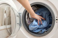 Una mano entrando en la secadora para sacar ropa